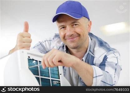 happy male technician repairing air conditioner