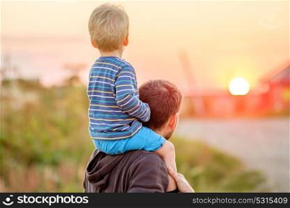 Happy man and his child having fun outdoors. Family lifestyle rural scene of father and son in sunset sunlight.