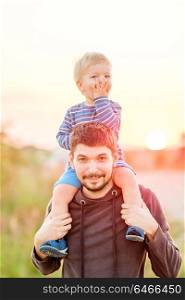 Happy man and his child having fun outdoors. Family lifestyle rural scene of father and son in sunset sunlight.