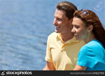 Happy Man and Woman Couple Sitting Outside by Water