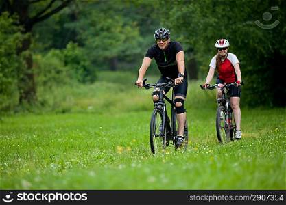 happy Man and woman exercising with bicycles outdoors, they are a couple in forest