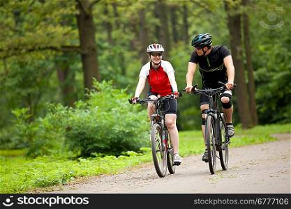 happy Man and woman exercising with bicycles outdoors, they are a couple in park