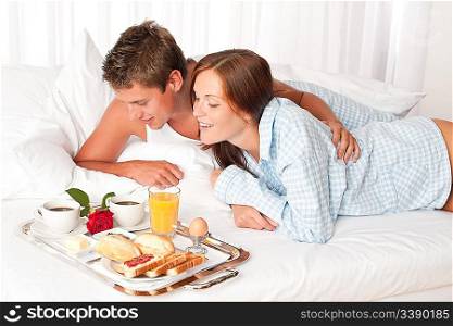 Happy man and woman having luxury hotel breakfast in bed together