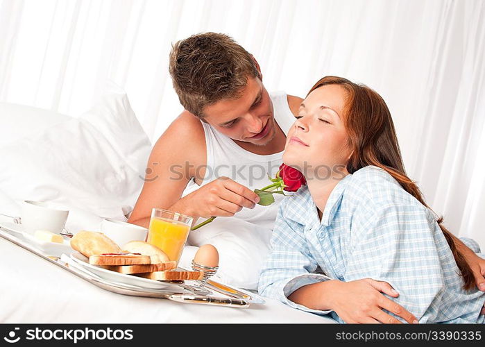 Happy man and woman having luxury hotel breakfast in bed together