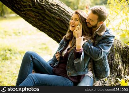Happy man and woman using smartphone in autumn park