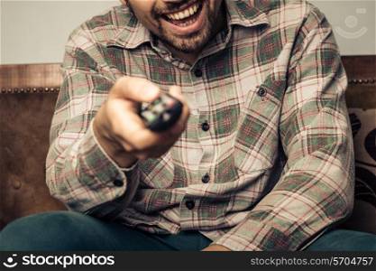 Happy man changing channel with remote control