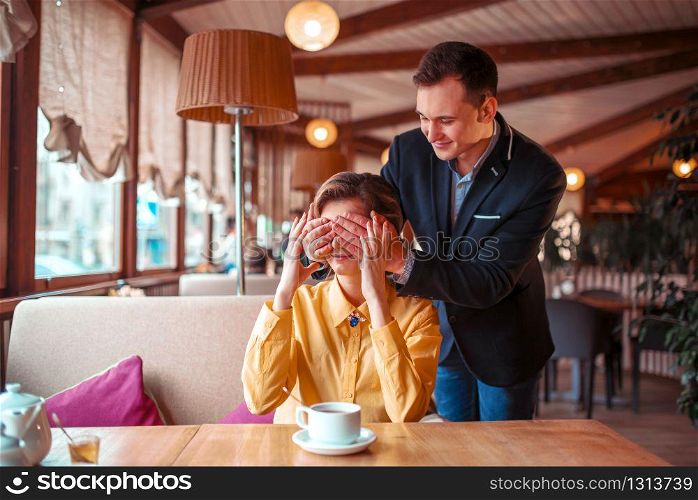 Happy man closes eyes hands to beautiful woman in restaurant. Romantic date of love couple