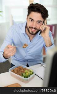 happy man eats a salad bowl in the office