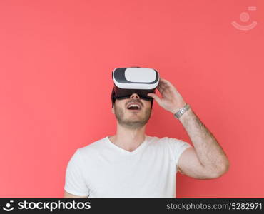 Happy man getting experience using VR headset glasses of virtual reality, isolated on red background