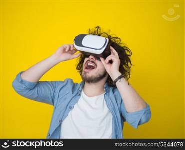 Happy man getting experience using VR headset glasses of virtual reality, isolated on yellow background