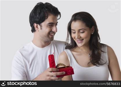 Happy man gifting bangles to woman against white background