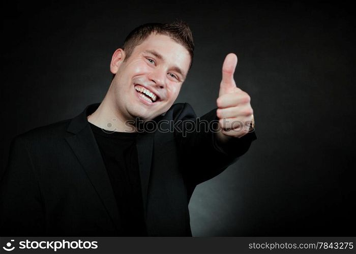 Happy man giving thumb up gesturing the all right symbol , ok sign black background