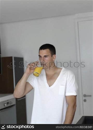 Happy man having orange juice with breakfast sitting at kitchen counter