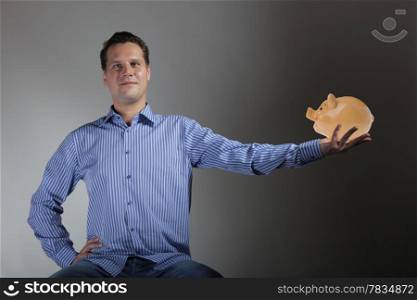 happy man holding a piggy bank gray background