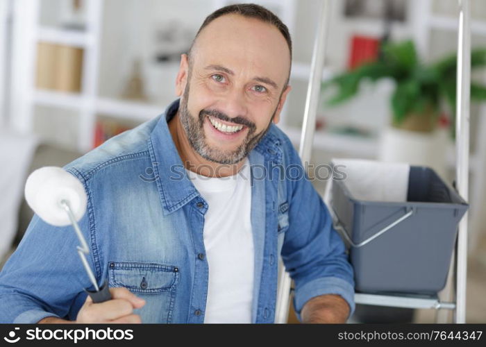 happy man holding a roller at home