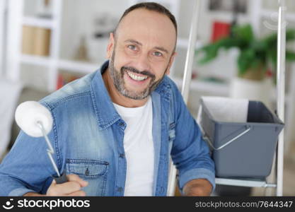 happy man holding a roller at home