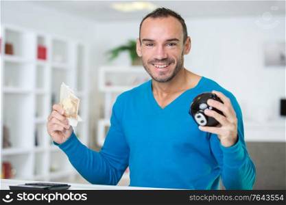 happy man holding piggy bank and banknotes