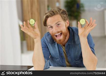 happy man holds cucumber in front of camera