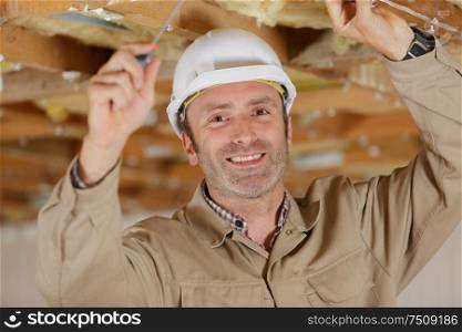 happy man in builder uniform installing suspended ceiling
