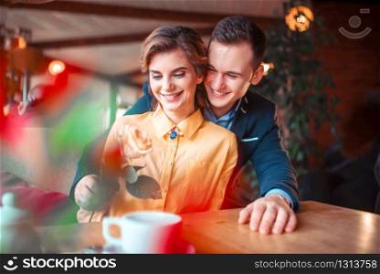 Happy man in suit gives rose to beautiful woman, romantic date in restaurant. Beautiful relationship of love couple