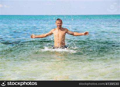 Happy man in the tropical sea with splashes