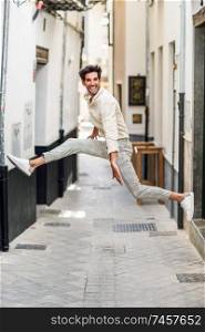 Happy man jumping in the street. Attractive Guy wearing casual clothes in urban background.. Young happy man jumping in the street.