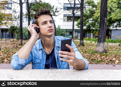 Happy man listening to music from a smart phone on city background