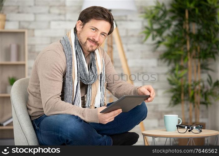 happy man on sofa with digital tablet