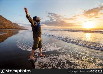 Happy Man on the sunrise in the beach. Travel and emotion concept