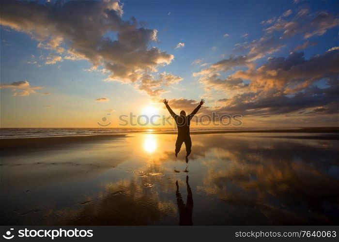Happy Man on the sunrise in the beach. Travel and emotion concept