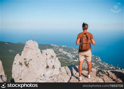Happy man on vacation in mountains. Tourist man outdoor on edge of cliff seashore