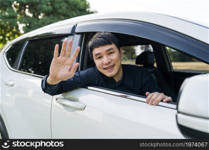 happy man open window of a car and raising his hand