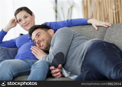 happy man touching belly of smiling pregnant woman