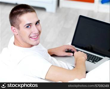 happy man using laptop and lying on the sofa
