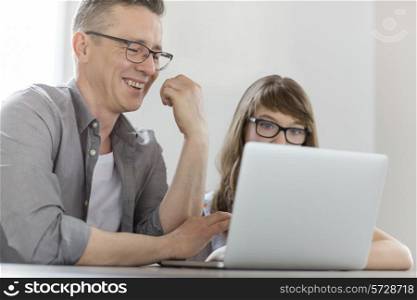 Happy man using laptop with daughter at home