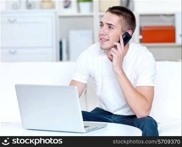happy man using mobile phone and laptop at home