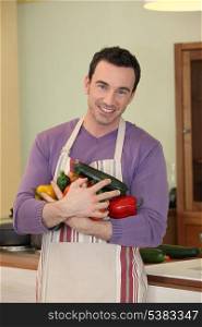 Happy man with apron holding vegetables