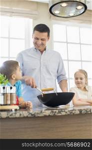 Happy man with children preparing food in kitchen