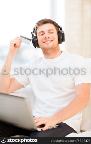 happy man with headphones and credit card listening to music at home