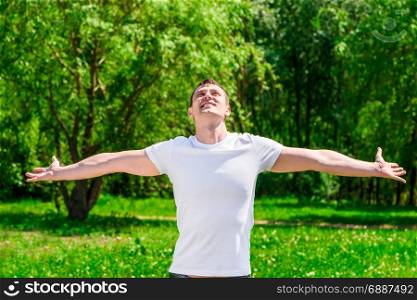 Happy man with open arms in a summer sunny park