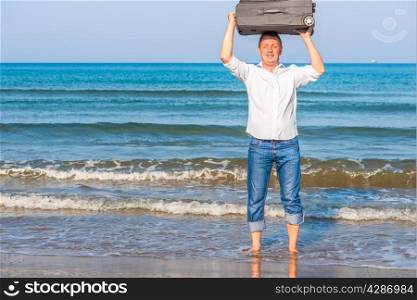 happy man with suitcase barefoot in the sea