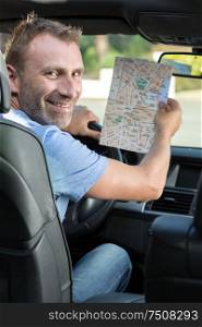 happy man with the map in the car