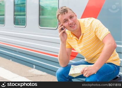 Happy man with the phone in anticipation of a trip on the train