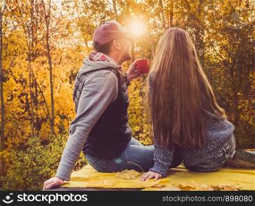 Happy married couple holding the US flag against the background of yellow trees and the setting sun. Happy relationship concept. Happy married couple holding the US flag
