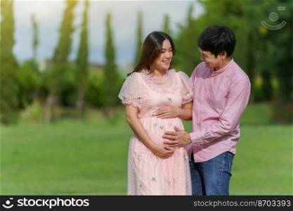 happy married couple is expecting a baby. man embraces his pregnant wife in the park