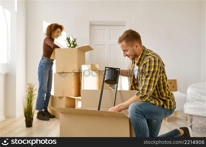 Happy married couple packing stuff in their flat. Overjoyed young family. Happy couple unpacking stuff in new flat