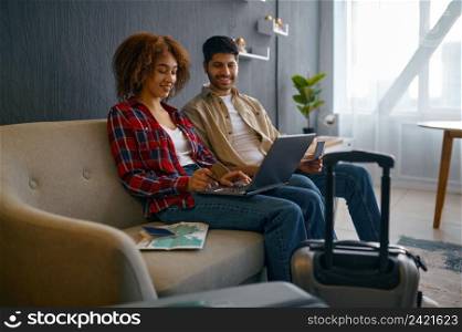 Happy married couple using laptop to pay for travel tickets and book hotel room online from home. Couple pay for travel tickets on laptop