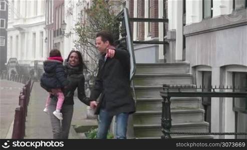 Happy married people, young man and woman with daughter, interracial marriage relationship, husband and wife. Mother walking in the street with child and husband, mom and dad with baby. Slow motion