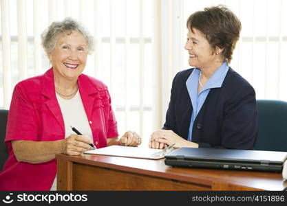 Happy mature businesswomen in the office signing paperwork.