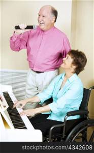 Happy mature couple performs music together. She is disabled.